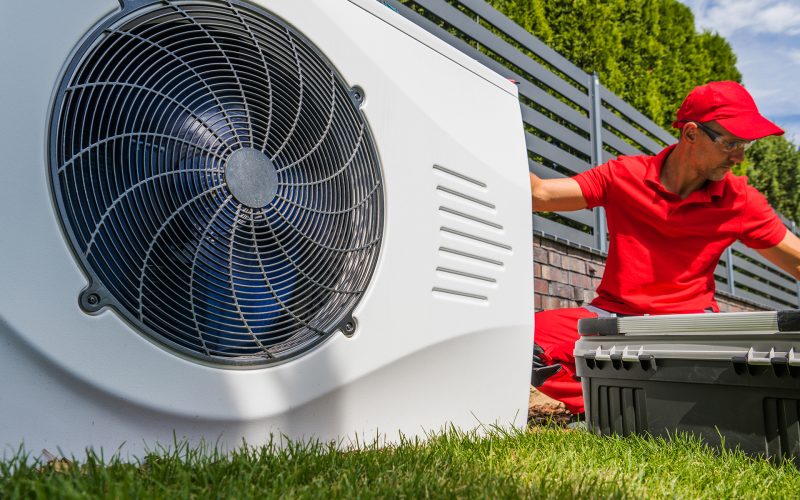 Professional HVAC Worker in His 40s Installing Swimming Pool Heat Pump Outdoor Water Heating Device. Energy Saving Technologies.